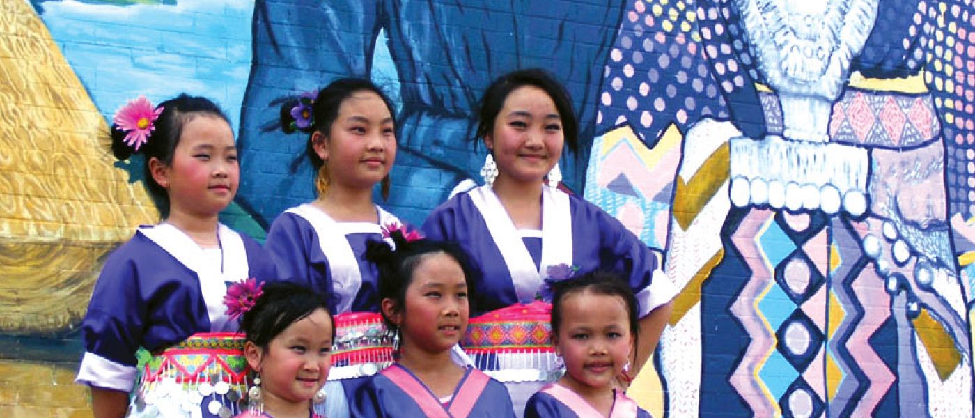 Young Hmong women in front of mural