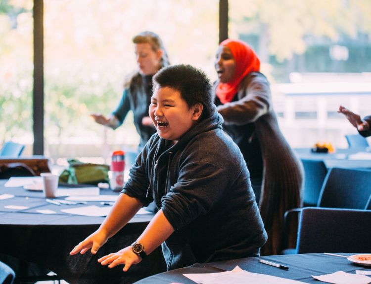 A young person smiling while doing an activity at the Youth Summit.