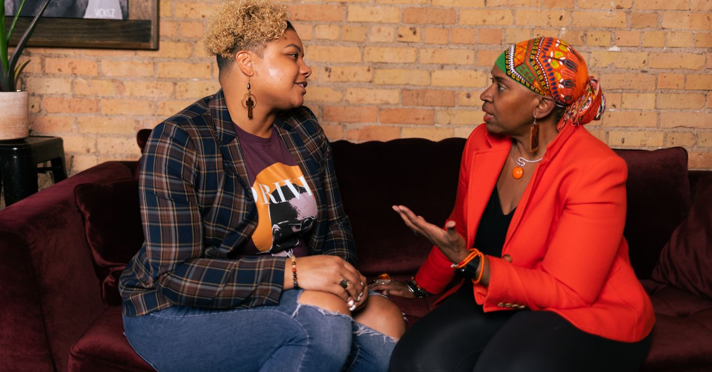 Drs. Brittany and Joi Lewis talking on a couch. 