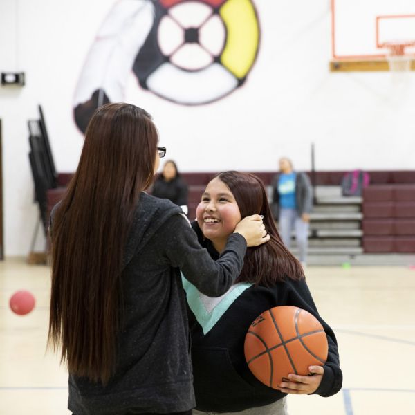 Two young women embrace on the basketball court