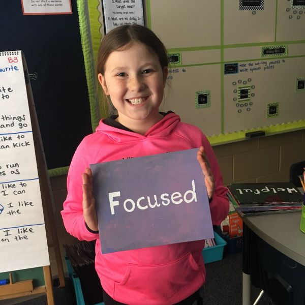 Girl at Jaguar Academy holding a sign that reads "Focused!"