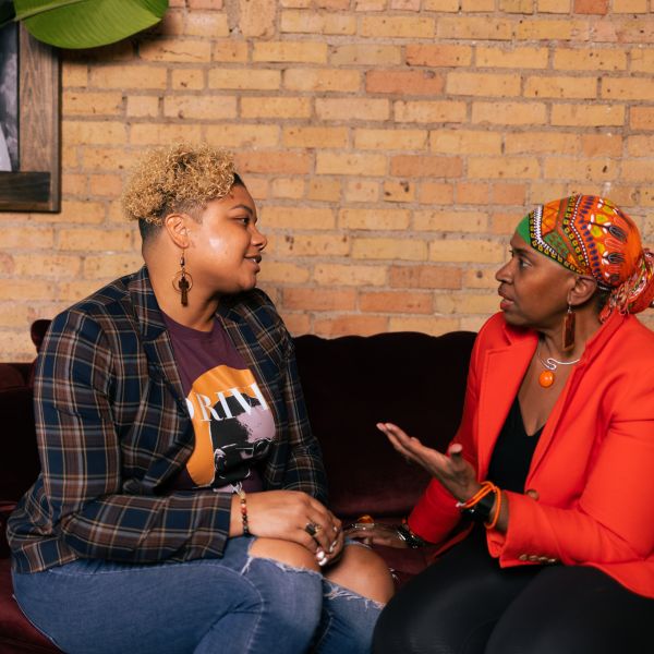 Drs. Brittany and Joi Lewis talking on a couch. 