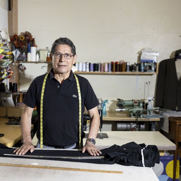 man measures pants on a table in a tailor shop to make alterations