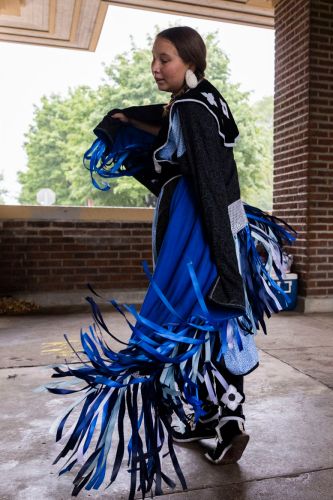 A Native dancer, dancing in traditional blue dress.