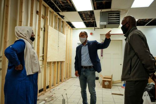 Henry Jiménez, center, talks with Minneapolis business owners about repairs