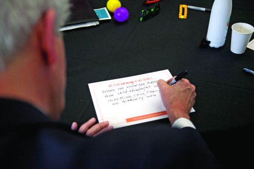 Over the shoulder shot of a man writing on a note card