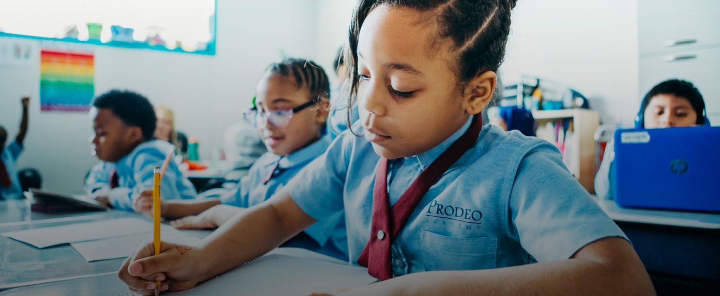 Young girl at Prodeo Academy sits at desk writing in notebook