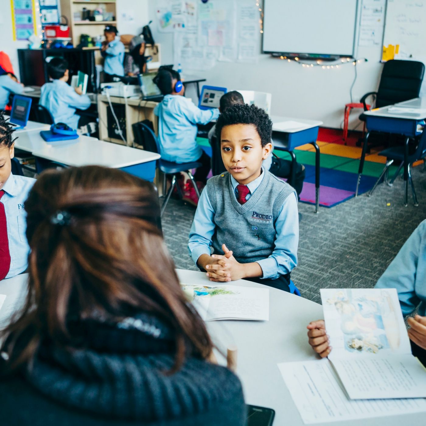 Boys in Prodeo Academy uniforms actively engaged by a teacher around a circular table
