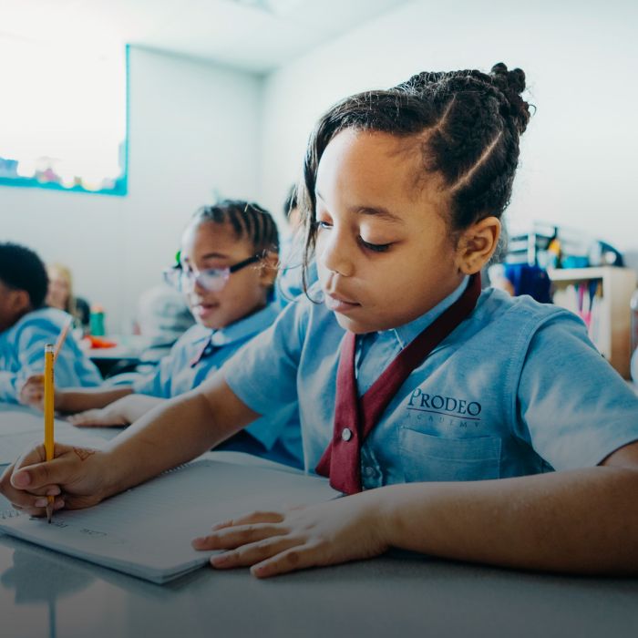 Young girl at Prodeo Academy sits at desk writing in notebook
