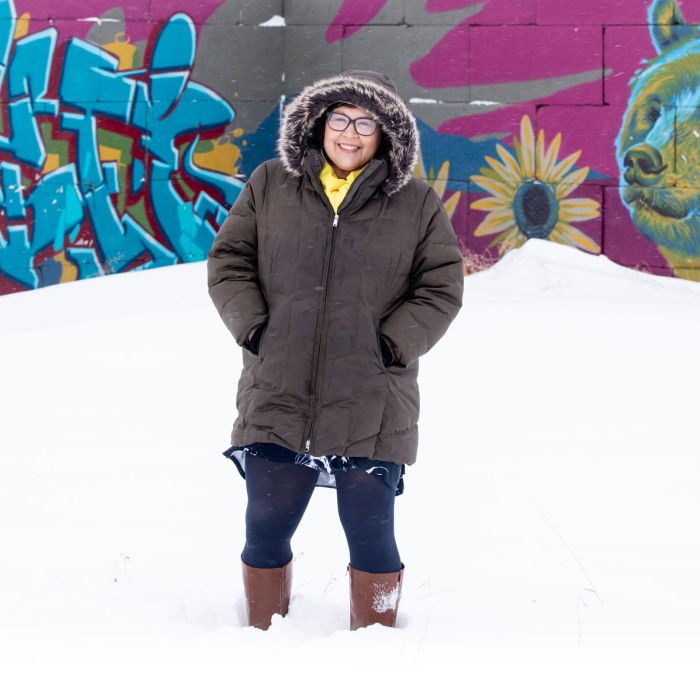 Julie Garreau in the snow and winter coat in front of graffiti art on wall